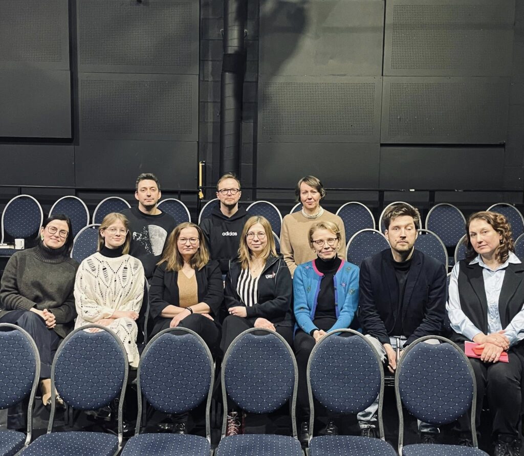 Tumesinistel teatritoolidel istub 10 inimest: 3 tagumises reas ja 7 esimeses reas.