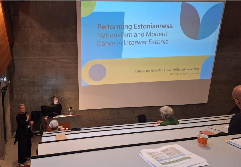 Pildil on konverentsisaal, kus seisab kõnepuldis Anne-Liis Maripuu. Ekraanil on slaid tekstiga "Estonian Street Dance: in-between Centre and Periphery".
