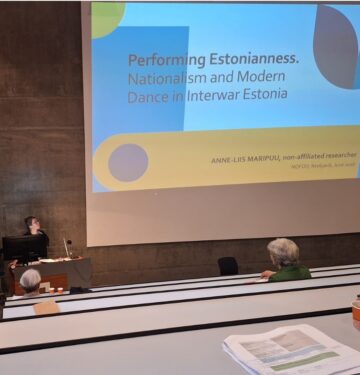 Pildil on konverentsisaal, kus seisab kõnepuldis Anne-Liis Maripuu. Ekraanil on slaid tekstiga "Estonian Street Dance: in-between Centre and Periphery".